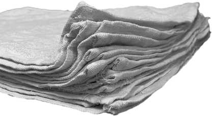 Closeup view from the corner of a stack of rags, without packaging, laid flat, and stacked neatly. Can clearly see the hemmed edges of the rags.